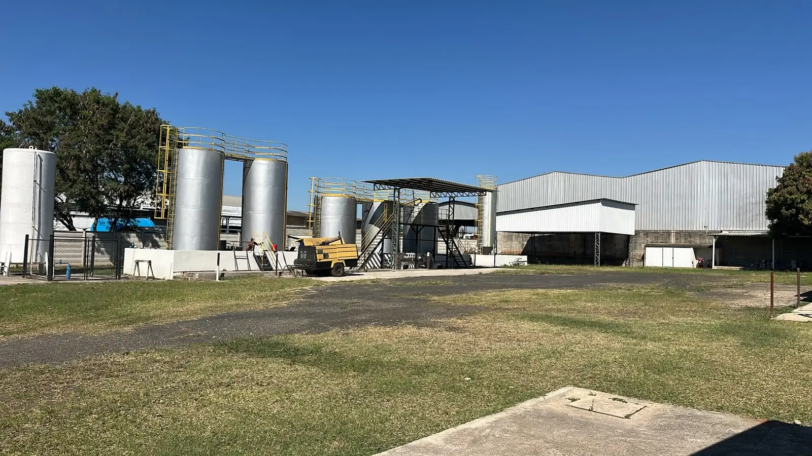 Área externa da fábrica com parque de tanques ao fundo